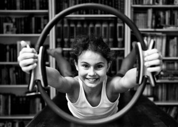 bambina che impugna un ring pilates braccia braccia tese e guarda la camera sorridente