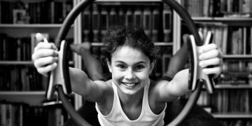 bambina che impugna un ring pilates braccia braccia tese e guarda la camera sorridente