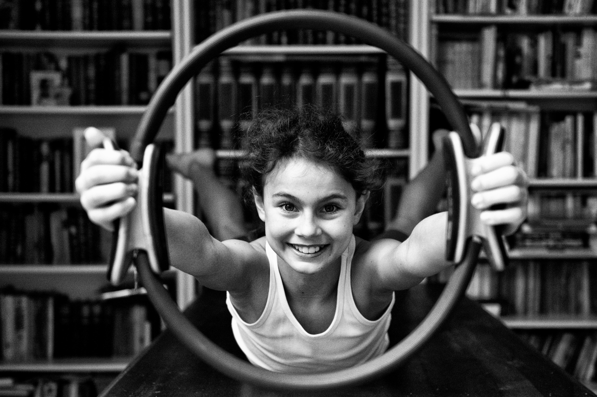 bambina che impugna un ring pilates braccia braccia tese e guarda la camera sorridente