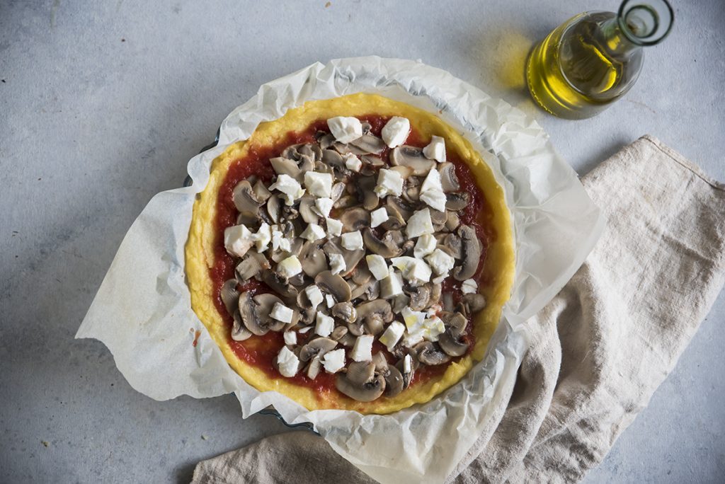 un teglia tonda su panno bianco con dentro la ricetta con polenta: pizza di polenta