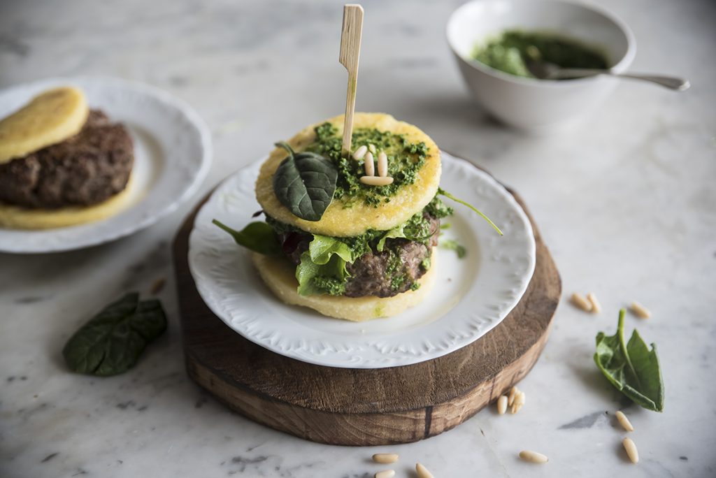 Hamburger di polenta con spinaci e carne 3 base di legno con un hamburger di polenta