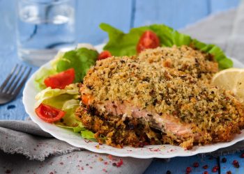 piatto con porzione di salmone in crosta, pomodorini e limone