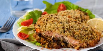 piatto con porzione di salmone in crosta, pomodorini e limone