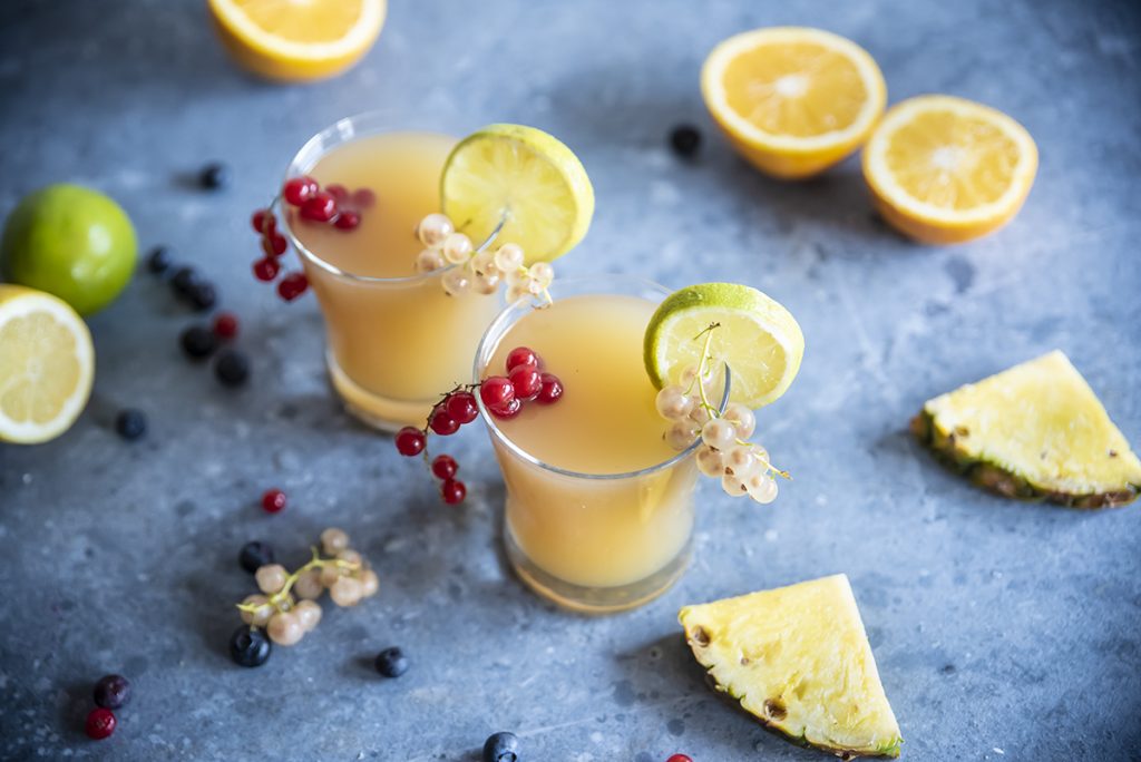 due bicchieri di cocktail analcolico Fruit Punch, ribes, fette e spicchi di limone