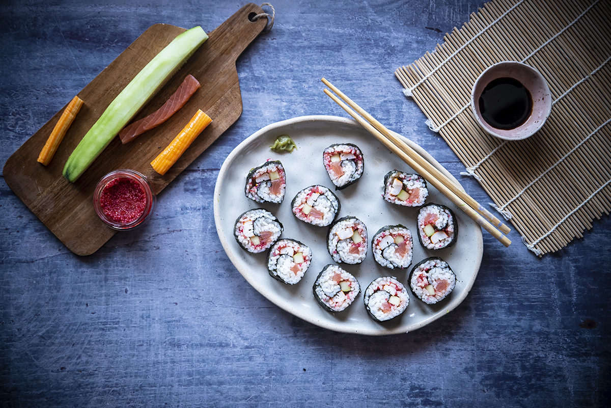 piatto con 12 futomaki con salmone e uova di lompo, bacchette, salsa di soia, vassoio con verdure e uova di lompo