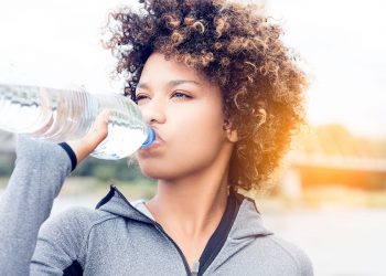 una giovane donna che beve acqua dalla bottigia