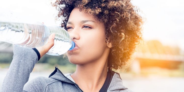 una giovane donna che beve acqua dalla bottigia
