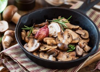 padella nera con manico con funghi trifolati e rosmarino