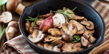 padella nera con manico con funghi trifolati e rosmarino