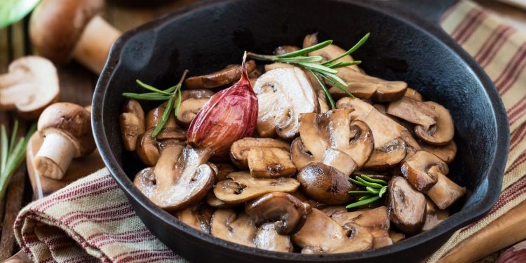 padella nera con manico con funghi trifolati e rosmarino