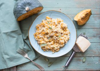 piatto azzurro su base azzurra pieno di risotto di zucca e porcini