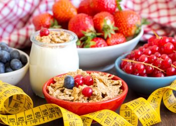 ciotole con mirtilli, ribes, fragole, frutta secca e barattolo di yogurt, e un centimetro