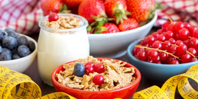 ciotole con mirtilli, ribes, fragole, frutta secca e barattolo di yogurt, e un centimetro