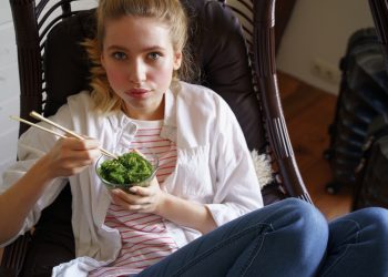 ragazza su una poltrona mentre mangia le alghe con le bacchette cinesi