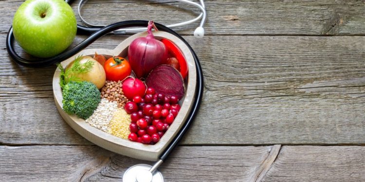 come abbassare il colesterolo: un contenitore a forma di cuore con alimenti salutari