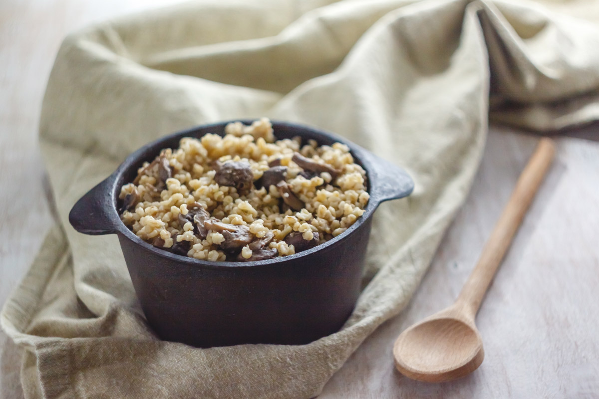 pirofila alta con il cous cous con funghi, un mestolo di legno