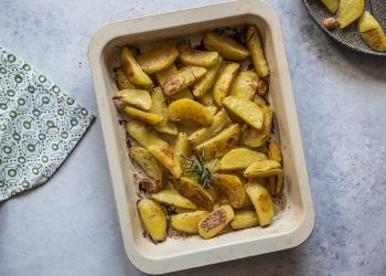 su un tavolo da cucina una teglia con patate al forno e rosmarino