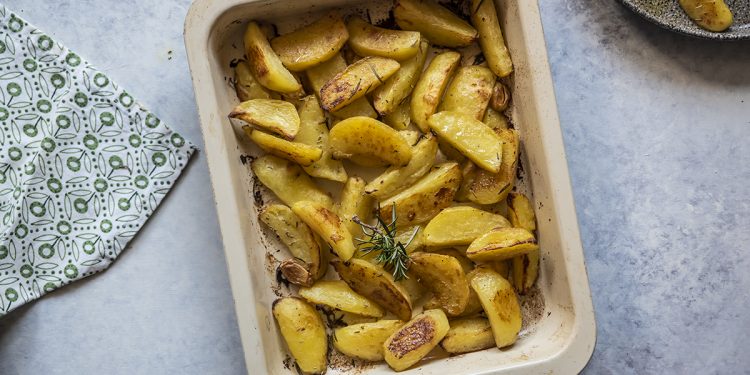 su un tavolo da cucina una teglia con patate al forno e rosmarino