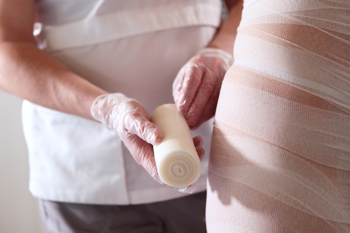 Come avere delle belle gambe: allenamenti, esercizi, cosa mangiare e trattamenti estetici 3 donna dall'estetista che si fa mettere bendaggi anticellulite per avere delle belle gambe