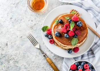 su un tavolo apparecchiato, piatto con pancake e frutti di bosco