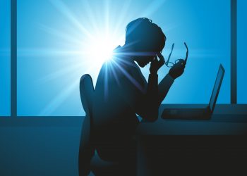 una donna in ufficio che stanca si massaggia gli occhi e che soffre di sindrome da burnout