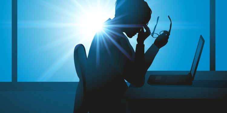 una donna in ufficio che stanca si massaggia gli occhi e che soffre di sindrome da burnout