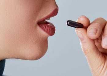 una giovane donna che sta per prendere una capsula di carbone vegetale