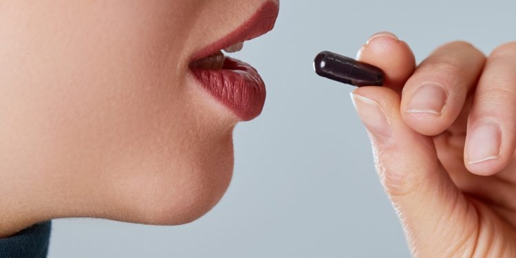 una giovane donna che sta per prendere una capsula di carbone vegetale