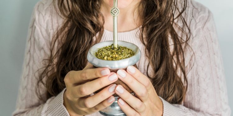 una giovane donna che bene del tè mate