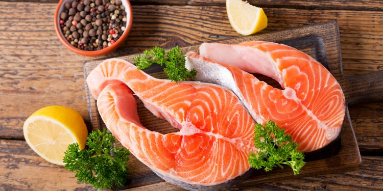 fresh salmon steaks with ingredients for cooking on a wooden table
