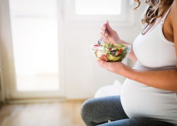 una donna incinta che mangia frutta per seguire una corretta dieta in gravidanza