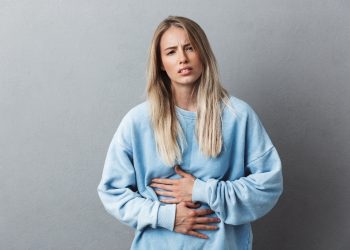 una giovane donna con la gastrite che si tocca la pancia