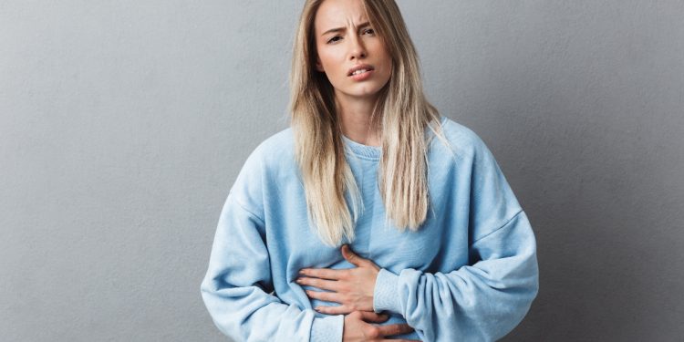 una giovane donna con la gastrite che si tocca la pancia