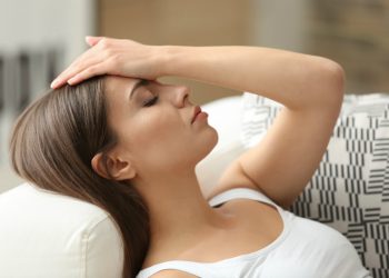 donna stesa a occhi chiusi con una mano sulla fronte