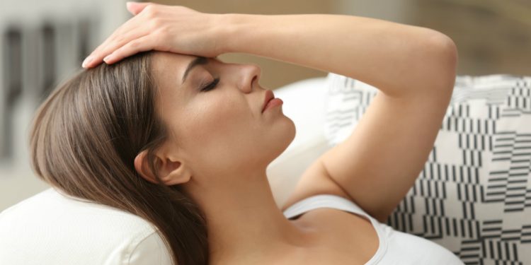 donna stesa a occhi chiusi con una mano sulla fronte