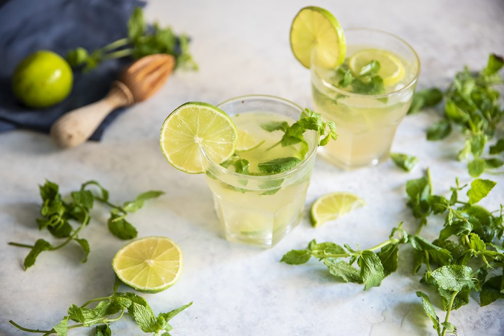 due bicchieri di cocktail analcolico Virgin Mojito, fette di limone e foglie sparse