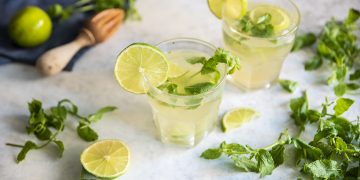 due bicchieri di cocktail analcolico Virgin Mojito, fette di limone e foglie sparse