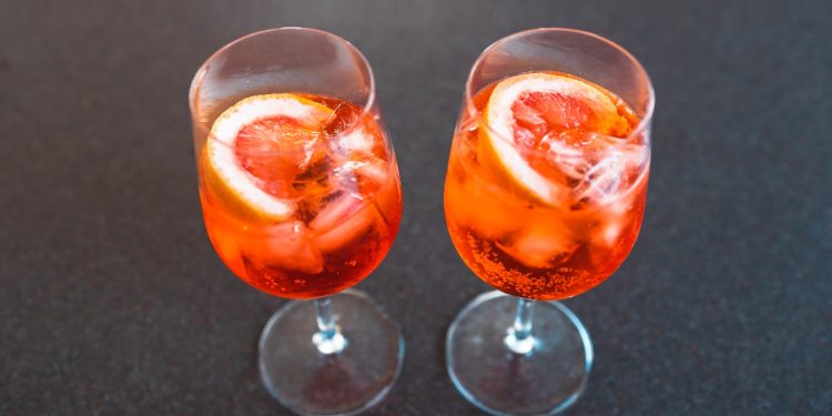 su base scura due bicchieri a calice pieni di cocktail Sptritz analcolico