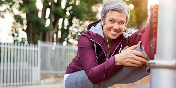 una donna cinquantenne che fa stretching per rimettersi in forma dopo i 50 anni