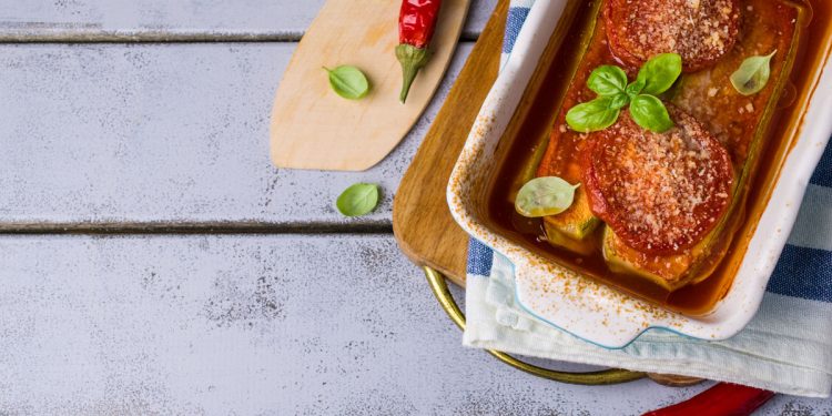 su base di legno azzurra una teglia con lasagne di tofu con parmigiana estiva