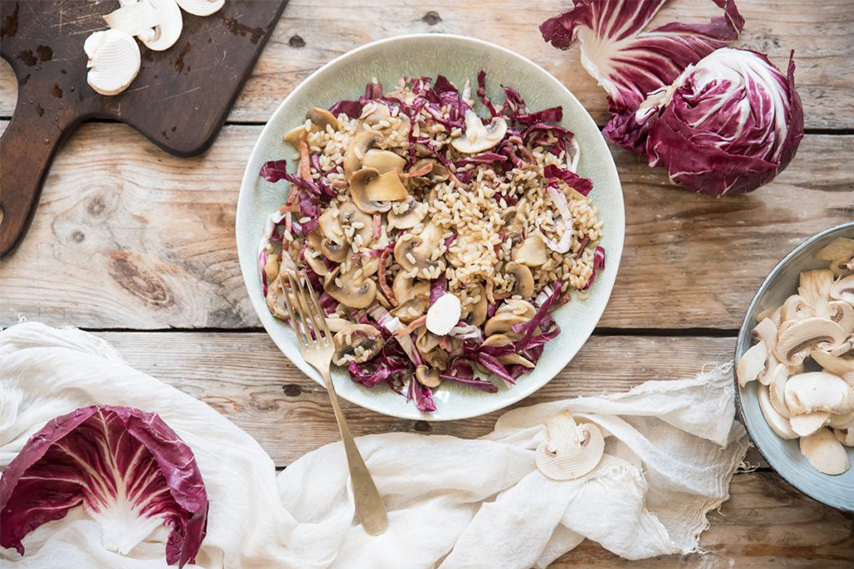 una ciotola bianca con insalata di riso autunnale, spicchi di radicchio sparsi