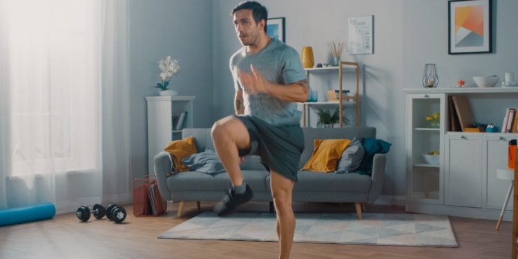 Un uomo nel soggiorno di casa pratica un programma di walk at home
