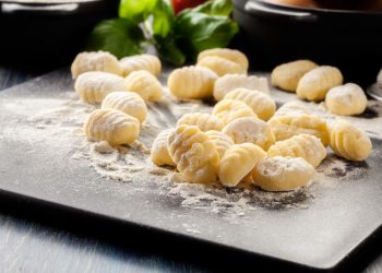 su piano da cucina: tagliere con in primo piano farina e gnocchi fatti in casa