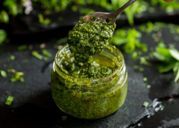 barattolo di vetro con salsa al pesto e cucchiaino
