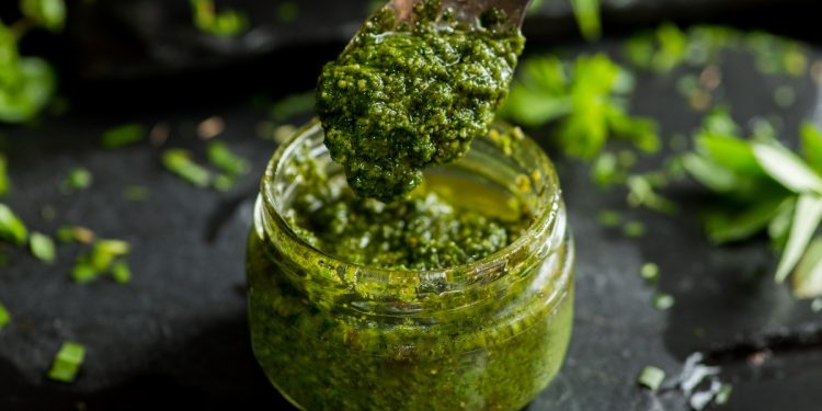 barattolo di vetro con salsa al pesto e cucchiaino