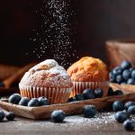 Muffin ai mirtilli con yogurt, ideali per colazione e merenda 2 un paio di muffin ai mirtilli con alcuni mirtilli sparsi accanto