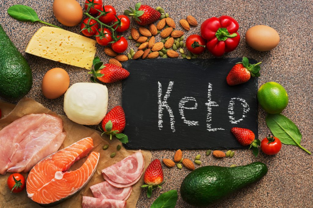 Dieta chetogenica: cosa mangiare e cosa evitare? 2 dieta chetogenica cosa mangiare: su un tavolo alcuni alimenti tipici della dieta keto con una lavagna nel mezzo e la scritta "ket"