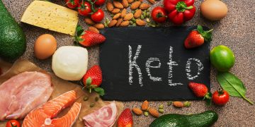 dieta chetogenica cosa mangiare: su un tavolo alcuni alimenti tipici della dieta keto con una lavagna nel mezzo e la scritta "ket"