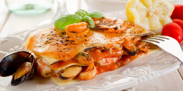 piatto bianco decorato con porzione di lasagne di pesce