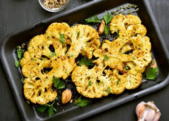 teglia scura rettangolare con due metà di cavolfiore arrostite
